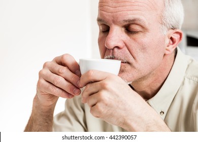 Close Up On Single Handsome Bearded Mature Man With Eyes Closed Sipping Coffee From Little White Tea Cup