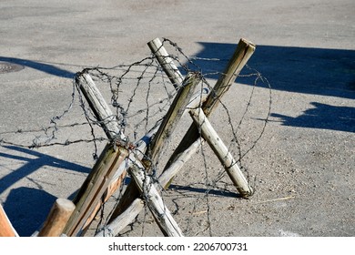 A close up on a small barricade made out of planks, logs, and sticks, with some barbed wire attached to it seen on a concrete floor on a Polish countryside during a military picnic or fair  - Shutterstock ID 2206700731