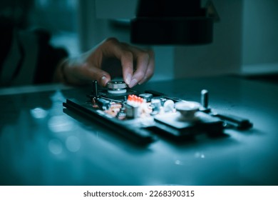 Close up on specialist engineer using small machine for controlling and testing new programing on circuit board for micro robotic arm welding. Technician maintenance working in microchip industry.