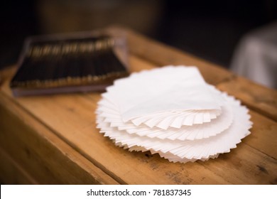 Close Up On A Spiral Stack Of White Cocktail Napkins On A Wood Shelf At A Bar 