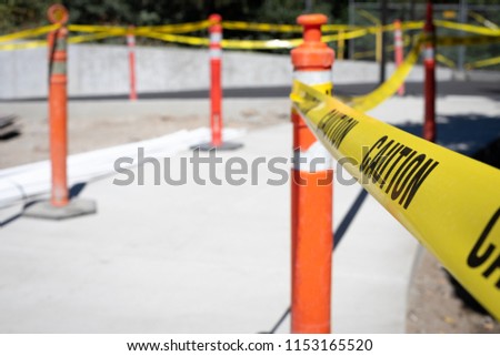 Close up on a strand of caution tape on a bollard cone, at a construction work site, with space for text on the left