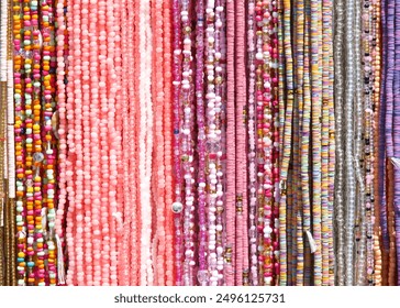 Close up on strings of beads in pinks and purples. Popular hair decorations in some cultures.