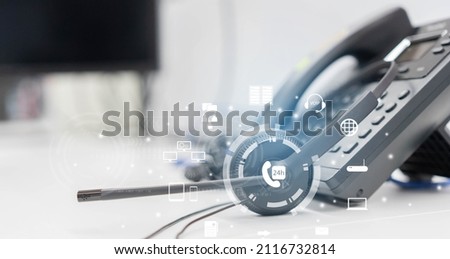 close up  on telephone VOIP devices with virtual interface of multitask icon background at office desk in operation room for customer service support (call center) concept