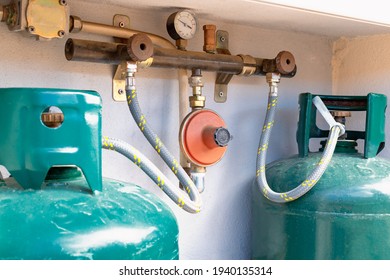 Close Up On Two Gas Cylinders Connected To The LPG Regulator And To The Residual Gas Detector. Double Gas Cylinders For Domestic Use With Outdoor Installation. View Of The Gas Control System.