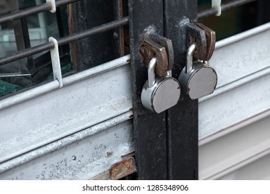 Close up on two old padlocks on a reinforced steel security gate, with space for text on the left
