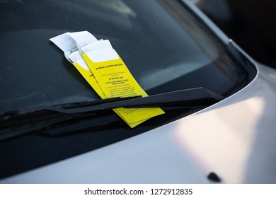 Close up on two parking tickets on the windshield of a parked car, with space for text on the right