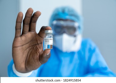 Close up on Vaccine. African American scientist in laboratory holding vial of coronavirus vaccine. The success of Virologists who invented the vaccine for Covid-19. Part of 2019-2020 global pandemic.