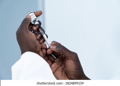 Close up on Vaccine. Hand of African American scientist in laboratory holding a syringe and vial of coronavirus vaccine. The success of Virologists who invented the vaccine for Covid-19.