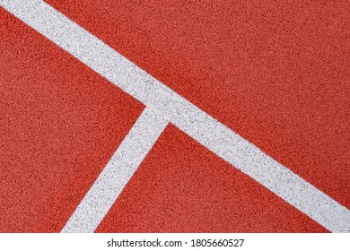 Close up on a white line in artificial red turf, on a street basketball, handball, volleyball, futsal, rugby, hockey and football field, in a sports background - Powered by Shutterstock