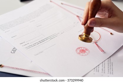 Close up on woman's notary public hand ink stamping the document. Notary public concept - Shutterstock ID 373299940