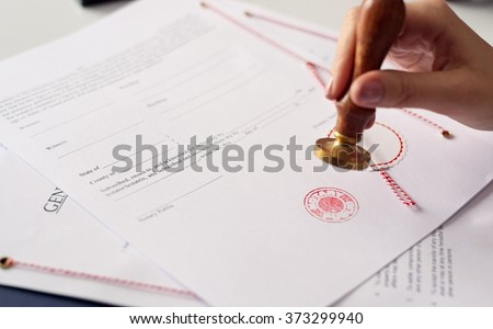 Close up on woman's notary public hand ink stamping the document. Notary public concept