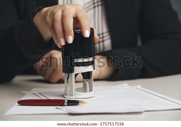 Close up on woman\'s notary public hand\
stamping the document. Notary public\
concept