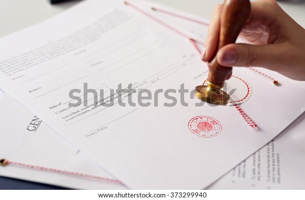 Close up on woman\'s notary public hand ink\
stamping the document. Notary public\
concept