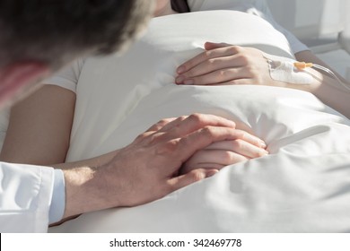 Close Up Of Oncologist Holding Hand Of Girl With Leukemia