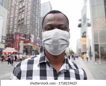 Close Up One Black African Man Wear Face Mask Looking At Camera Smile In The Eye At Urban Street With Crowd Of People Walking In Blurred Background Coronavirus Covid-19 Pandemic Outbreak