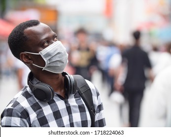 Close up of one black African man wear face mask looking up away  people portrait with mask at urban street with crowd of people walking in blurred background coronavirus Covid-19 pandemic outbreak - Powered by Shutterstock