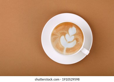 Close Up One Cup Full Of Cappuccino Coffee On White Saucer Over Brown Paper, Elevated Top View, Directly Above