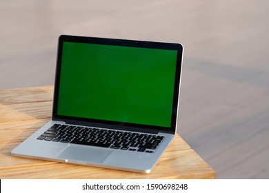 Close Up One Green Screen Laptop Computer On Wooden Table. Blur Background