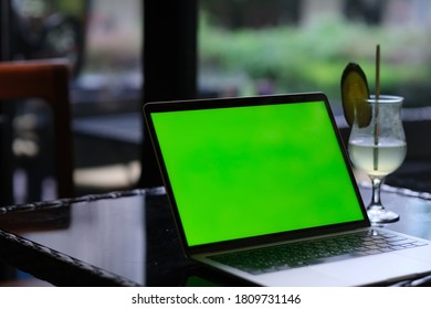 Close Up One Green Screen Laptop Computer On Cafe Table With Glass Of Drink. No People. Blur Background