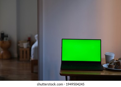 Close Up One Green Screen Laptop Computer On Table. Blurred Home Interior Background