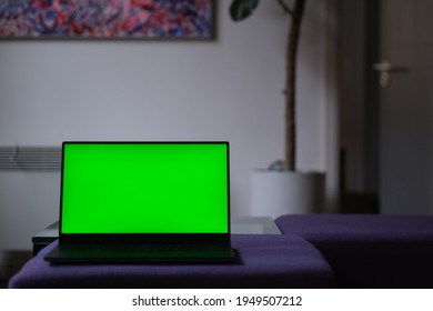 Close Up One Green Screen Laptop Computer At Home. Blurred Home Interior Background