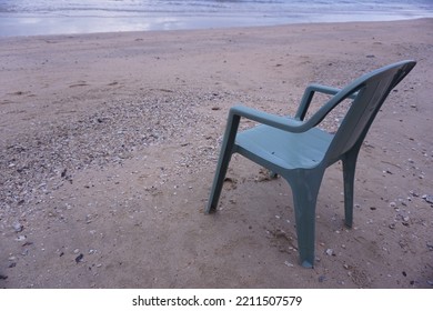 Close Up Of One Light Green Plastic Chair  Alone On The White Sand And Sea. The Morning Light With Copy Space In Thailand. 