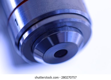 Close up of one microscope lens with blue tint, soft focus and bright background