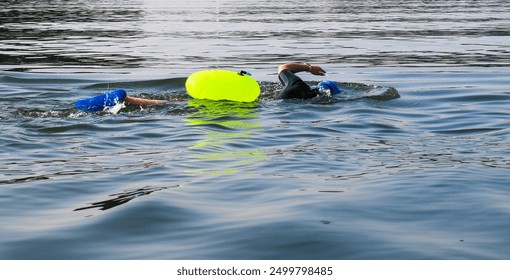 A close up of One swimmer swimming in the open water wearing a neon green safety flotation device in the Long Island Sound. - Powered by Shutterstock