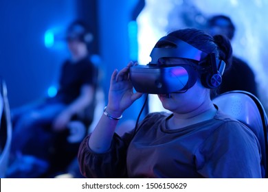 Close Up One Young Female Holding VR Headset Watching Movie. Blur People Sitting On Chair Experience VR Under Blue Lights