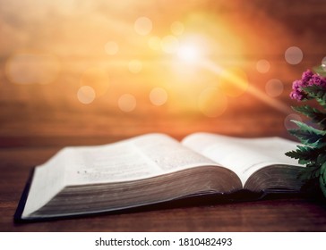 Close Up Of Open Bible And Flower With Sun Light Effected On Wooden Table, Christian Background With Copy Space