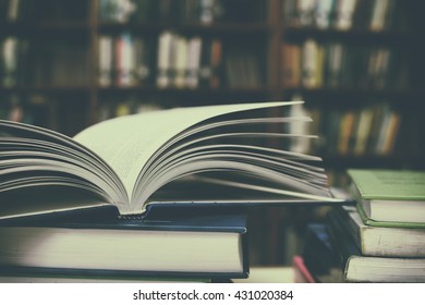 Close up of open book and Stack of books on desk with vintage filter blur background - Powered by Shutterstock