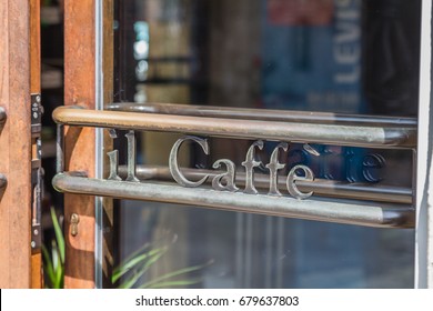 Close Up Of Open Glass Door With Original Metal Handle With Sign In Italian 