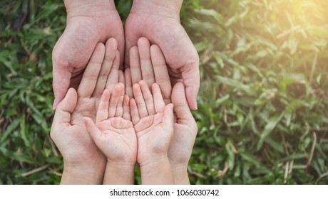Close up open hands of man and woman and kid with palm up isolated on green grass background. Family together helping green environment protection harmony community and caring concept 