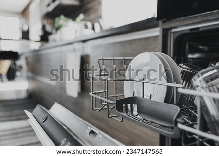 Close up of opened automatic stainless built-in dishwasher machine inside modern home kitchen with clean utensil. Household, housekeeping domestic life. Opening and closing washing machine