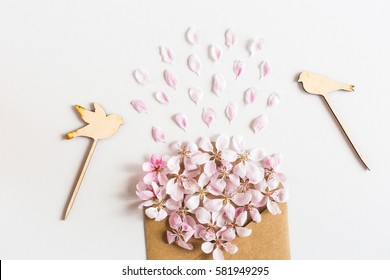 close up of opened craft paper envelope full of spring blossom sacura flowers on white background. top view. concept of love. Flat lay.