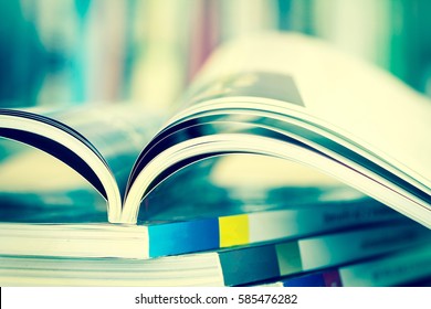 Close up opened magazine page with  blurry bookshelf background for bublication concept , extremely DOF with vintage retro color tone