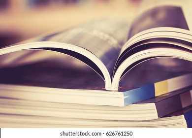Close up opened magazine page with  blurry bookshelf background for publication concept , extremely DOF with vintage retro color tone