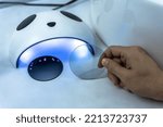 Close up optometris hand holding photochromic eyeglass len to test in LED light testing machine in optical clinic, optician testing photochromic plastic len in optic clinic,  selective focus 