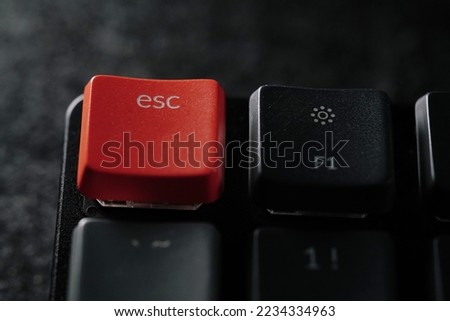 Close up of orange esc button on black keyboards.