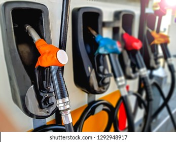 Close Up Orange Fuel Nozzle With Blurred Colorful Petro Nozzles At Gasoline And Diesel Gas Station. Petro Pump Concept.