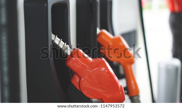 Close up orange Gasoline fuel nozzle for\
car refueling at pump gas station\
service