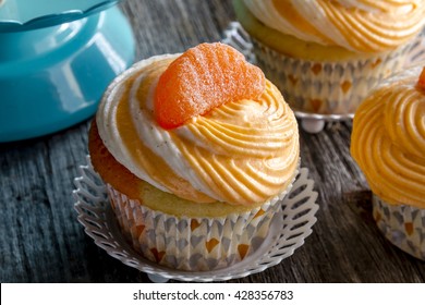 Close up of orange and vanilla bean swirled cupcake sitting on wooden table