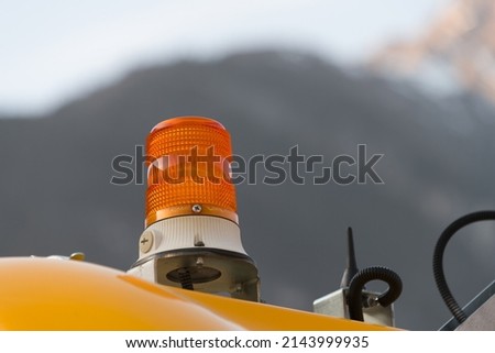 Close up of orange yellow rotating beacon torch lamp as warning light when using work machines and equipment in front of mountains and blue sky Imagine de stoc © 