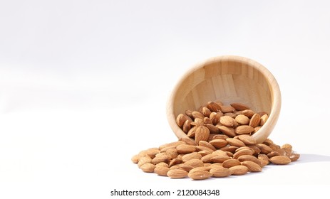 
Close Up Of Organic Brown Raw Almond Seed Heap With Wooden Circle Bowl On White Background. Healthy Nuts Eating And Kernel Concept