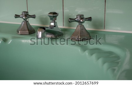 Close up of original green vintage retro 1930s deco wash basin and stainless steel taps.