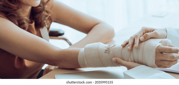 Close Up Of Orthopedic Doctor Investigates Woman Patient Broken Arm Cover With Splint Plaster Cast. Trauma Can Happen After People Fall And Physically Bones Fracture By Accident. Rehab Center Services