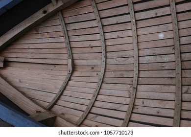 Close up outdoor view from above of part of a small wooden boat on the water. Particular design with wooden strips at the interior of the canoe. Curved shapes with clear brown lines. Abstract image.   - Powered by Shutterstock