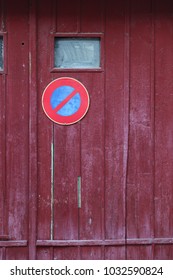 Close up outdoor view of an old wooden garage door with the symbol no parking. Small windows, purple planks with the circular sign in blue and red. Rough vintage texture. Abstract architectural image. - Shutterstock ID 1032590824
