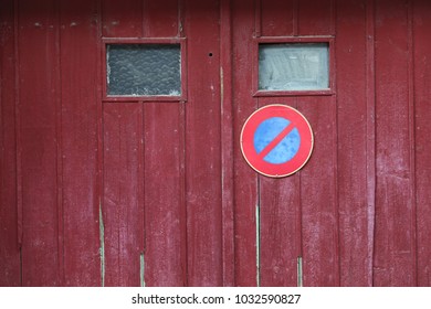 Close up outdoor view of an old wooden garage door with the symbol no parking. Small windows, purple planks with the circular sign in blue and red. Rough vintage texture. Abstract architectural image. - Shutterstock ID 1032590827