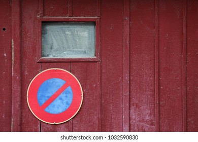 Close up outdoor view of an old wooden garage door with the symbol no parking. Small windows, purple planks with the circular sign in blue and red. Rough vintage texture. Abstract architectural image. - Shutterstock ID 1032590830